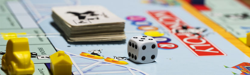 Monopoli lautapeli. Lautapelin päällä on pelinappuloita, noppa ja pelikortit.