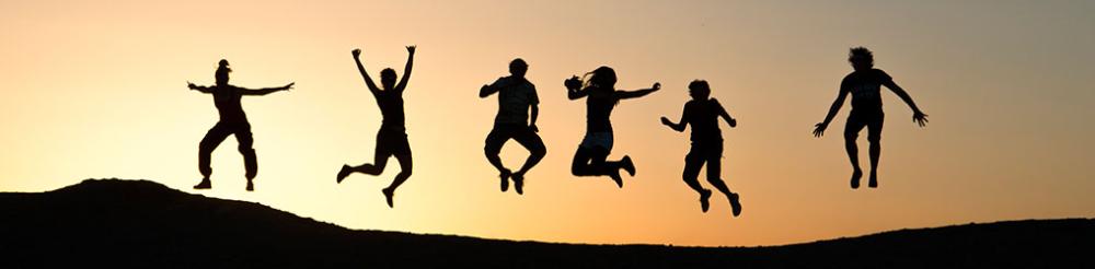 Ryhmä ihmisiä hyppää iloisesti ilmassa samaan aikaan.